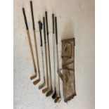 A collection of vintage golf clubs together with a vintage pencil canvas and leather golf club bag
