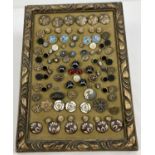 A collection of decorative vintage buttons on a framed velvet pad. To include banded agate, micro