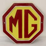 A painted cast iron octagonal shaped MG wall plaque. In red, yellow and white and complete with