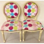 A pair of wooden framed balloon back style chairs, painted cream. Modern spotted design upholstery