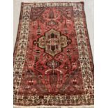 A vintage wool rug with red/brown ground and geometric design. Slightly stretched to one end.