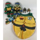 A collection of Teenage Mutant Ninja Turtle toys. To include: a play apron, Raphael and Leonardo