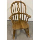 A child's light wood Windsor Rocking chair with turned legs and supports and cut out detail to back.