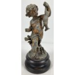 An antique hollow pewter figurine of a child holding a lamb, mounted on a circular wooden plinth.