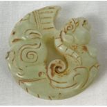 A carved jade roundel with mythical creature detail. Carved detail to both sides. Approx. 5.5cm