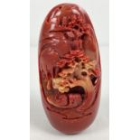 An oriental red coloured stone with carved scenic detail to one side. Depicting a boat on a river