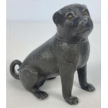 An antique pewter pounce pot modelled as a pug dog, with small amber glass eyes. Approx. 9cm tall.