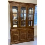 A large mirror backed, solid wood heavy display unit with glass doors and cupboard base. Base has