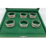 A boxed set of 6 silver napkin rings with channeled design and copper ring detail. Each stamped