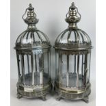 A large pair of circular shaped silver finish lanterns with glass panels and hinged opening door.
