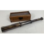 A reproduction 3 drawer brass telescope with engraved lettering, in a glass topped wooden box.