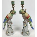 A pair of ceramic candlesticks modelled as parrots sitting atop a stump. With flower and insect
