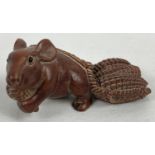 A carved wooden netsuke modelled as a mouse pulling a basket of ears of corn. Set with small
