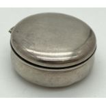 A small antique silver circular pill box with hinged lid. Hallmarks to inside on both base and lid