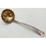 A George III silver sauce ladle with engraved handle of scroll and foliate design. Gilt lined bowl