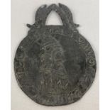 A medieval style lead medallion with kings heads to each side and wheatsheaf and fish detail to top.