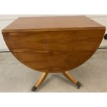 A modern reproduction satin wood veneer drop leaf table with pedestal base. Four metal claw feet