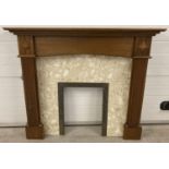A cream marble and brass fire surround with carved wooden mantle. Column detail and carved floral