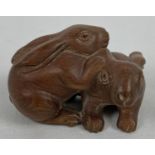 A small carved wooden figure modelled as 2 rabbits. Approx. 3.5cm tall x 5.5cm long.