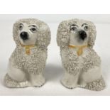 A pair of antique Staffordshire ceramic poodle figurines with hand painted yellow collars. Chip to