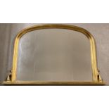 A large gilt framed over mantle mirror. With curved top and small scroll detail to both sides.