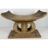 A vintage light wood African Ashanti "Golden stool" with curved seat and carved detail. Vendor