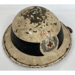 A British WWII 1940 MkII steel helmet painted white with circumferential black band. Hand painted