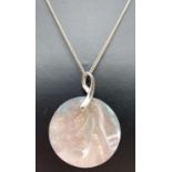 A large circular mother of pearl disk pendant with contemporary design silver bale on an 18" curb