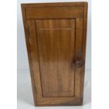 A vintage dark wood wall hanging cabinet with interior compartments, panelled door and knob