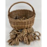 A vintage wicker shopping basket together with a quantity of large wooden curtain rings. Rings