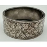 A Victorian silver wide bangle with ivy leaf engraved design to one half and push clasp.