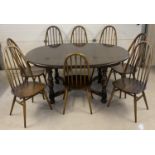 A vintage Ercol dark wood extending dining table and 8 spindle backed chairs. Chunky legged table