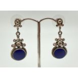 A pair of silver drop style earrings set with round cut lapis lazuli stones and detailed with scroll