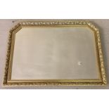 A large gilt framed over mantel mirror with shaped top. Approx. 73cm x 103cm.