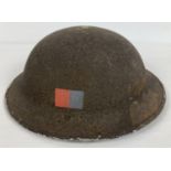 A British WWII MkII steel helmet, 1942, with Royal Signals flashes. Painted with late war brown