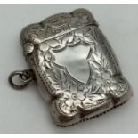 A decorative Edwardian silver vesta case with blank cartouche to front, surrounded by an engraved