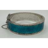 A modern silver and turquoise coloured guilloche bangle with push clasp and safety chain. Floral