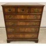 A modern reproduction solid dark wood 7 drawer chest with brass drop down handles. 3 small drawers