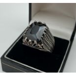 A silver statement cocktail ring set with a large octagon cut black spinel stone. Decorative pierced