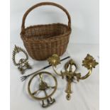 A vintage wicker shopping basket containing a small collection of brass ware items. To include a