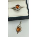 A small spiral design ring set with a round amber cabochon. Together with a modern design heart