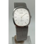 A men's Cyma by Synchron wrist watch with silver tone metal mesh strap. Brushed silver tone face