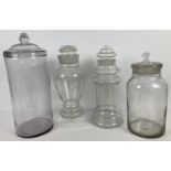 4 large antique glass apothecary jars with decorative finials to lids. 2 jars are ornately shaped.
