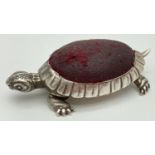An Edwardian silver novelty pin cushion in the form of a tortoise with worn red fabric cushion.