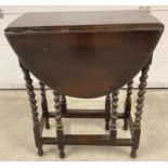 A small vintage dark oak drop leaf, gate leg barley twist table.