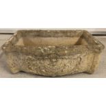 A stone trough style garden planter with carved cherubs and floral detail to front.