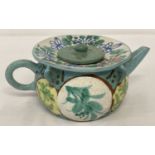 A small terracotta Oriental teapot with blue/green glaze and hand painted floral detail.