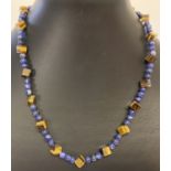 A lapis lazuli and square shaped tigers eye beaded necklace with flower shaped T bar clasp.