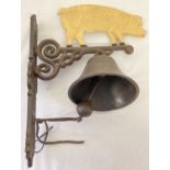 A painted cast metal wall hanging garden bell with pig design.