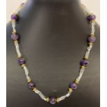 A 17" amethyst and aquamarine beaded necklace with gold tone S shaped hook clasp and spacer beads.